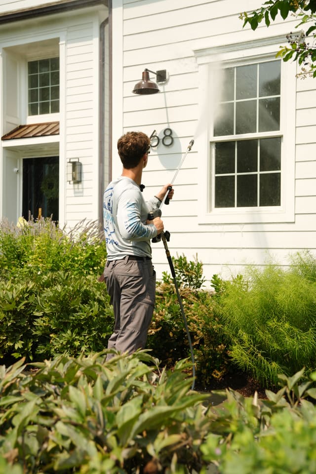 Rinsing detail work along the siding of a home