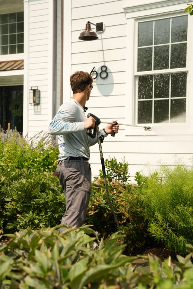 Washing windows and white siding on a home exterior